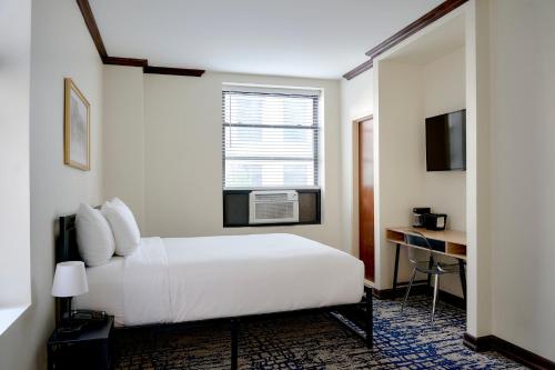 a hotel room with a bed and a desk at Night Hotel Broadway in New York
