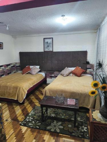 a bedroom with two beds and a coffee table at Minidepartamento central en Ambato, para 1 a 8 personas en 3 Camas y un colchon in Ambato