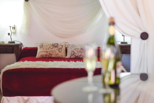 a bedroom with a red bed and a table with a bottle of wine at las moraditas in Chascomús