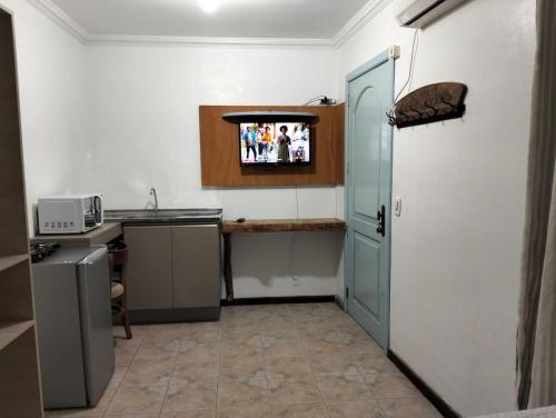 a kitchen with a sink and a tv on the wall at kitnet xixo 02 in Gramado