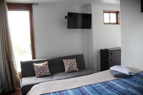 a bedroom with a couch and a flat screen tv at Habitaciones Barrancas en San Antonio - Cabañas y Mini Departamentos in San Antonio