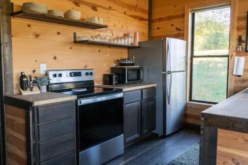 a kitchen with a stove and a refrigerator at Bourbon Barrel Cottages #5 on Ky Bourbon Trail in Lawrenceburg