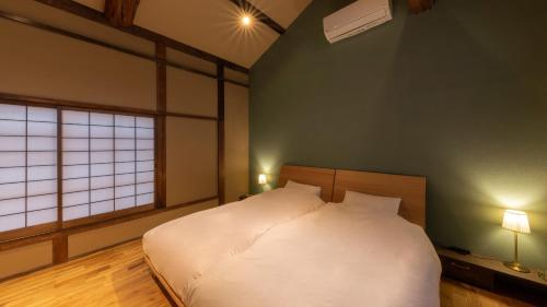 a bedroom with a white bed and a window at まちや倶楽部別館 in Omihachiman