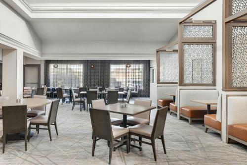 a dining room with tables and chairs and windows at Chicago Marriott Midway in Bedford Park