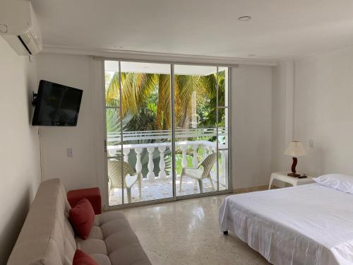 a bedroom with a bed and a couch and a balcony at LAGOS DEL PEÑON 180 metros in Girardot