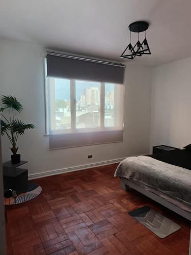 een slaapkamer met een bed en een groot raam bij GuestHouse in Santiago