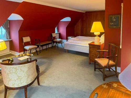 RingeにあるManor House Overlooking Fields And Gardenの赤い壁のベッドルーム1室、ベッド1台、椅子が備わります。