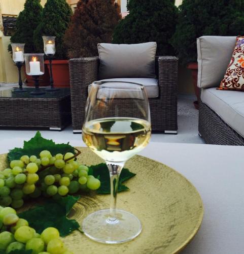 a glass of white wine and grapes on a table at Venetian Palace Chania in Chania Town