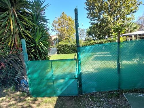 a green fence with a tennis court behind it at Casa con giardino in Cecina