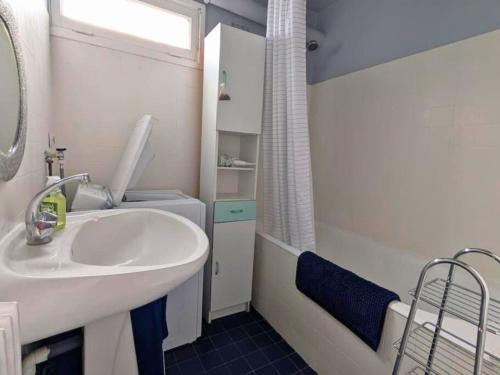 un baño con lavabo blanco y ducha en La Clé de Jane, en Chatou