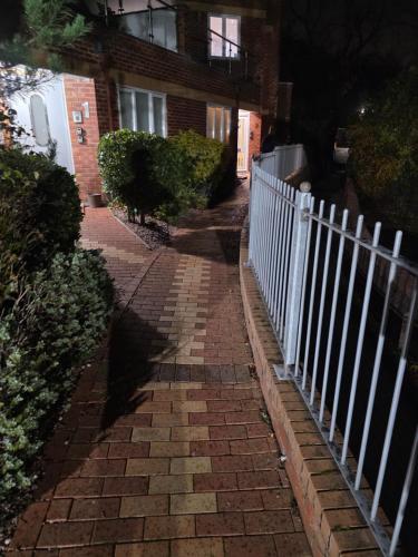 Ein gepflasterter Gehweg mit einem weißen Zaun vor einem Gebäude in der Unterkunft School Path in Ironbridge