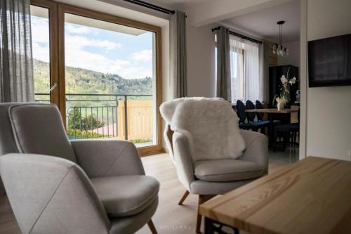 a living room with two chairs and a large window at Bella Monte in Szczyrk