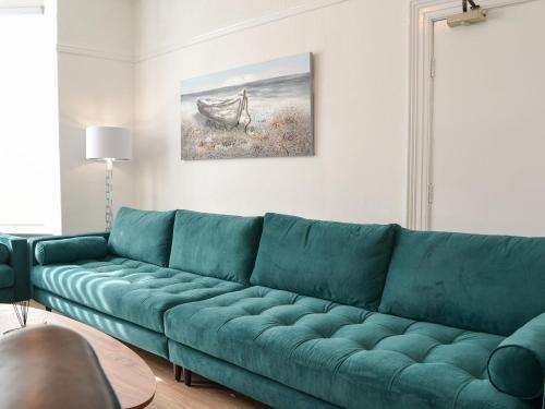 a green couch in a living room with a painting at Kilburn House in Bridlington