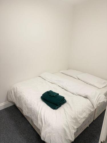 a white bed with a green towel on it at Saunders house in Gillingham
