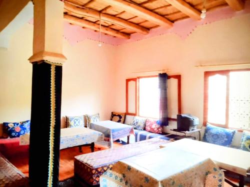 a living room with couches and a tv and windows at Riad hotel Étoile dades Camping in Aït Ali Ou Allah