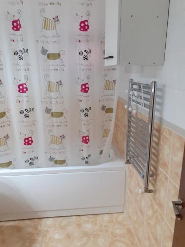 a bathroom with a shower curtain with a cat on it at Promenada Mall Apartment4you in Craiova