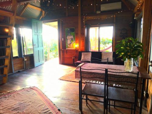a dining room with a table and chairs and windows at La Parada del Pelicano, El Ranchito Surf in Malena