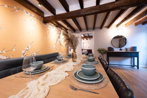 a dining room with a long table with plates and wine glasses at Charming 3BR Cottage Sleeps 8 - 15 Mins to Centre in Wickhambreaux