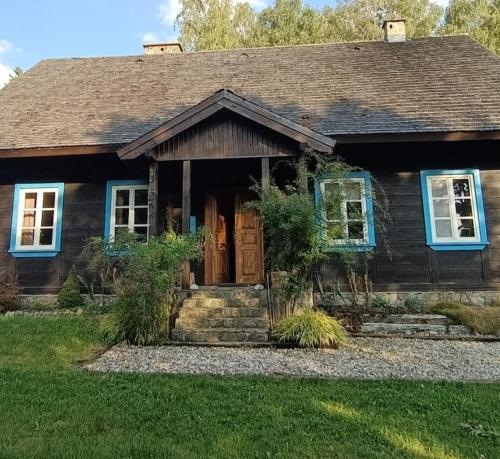 een houten huis met blauwe ramen en een deur bij SoBądź - Po prostu bądź in Sobącz