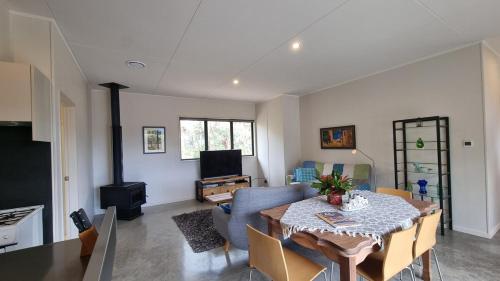 a living room with a dining room table and a couch at Pheasant Hill Hideaway 10 min to Waihi Beach in Athenree
