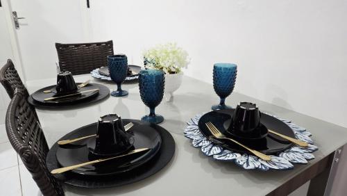 a table with black plates and hats and blue vases at Apt perto do shopping in Petrolina
