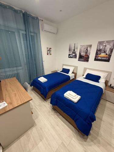 twee bedden in een kamer met blauwe lakens bij DRIL Host 2 in Brindisi