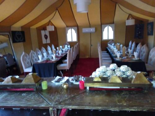 a room with tables and chairs in a room with food at Afraklie Camp in Merzouga