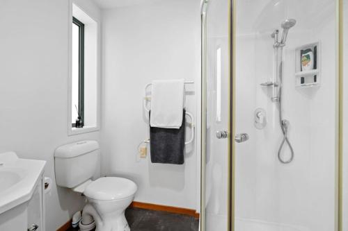 a white bathroom with a shower and a toilet at Water's Edge Stay in Central Whangarei in Whangarei