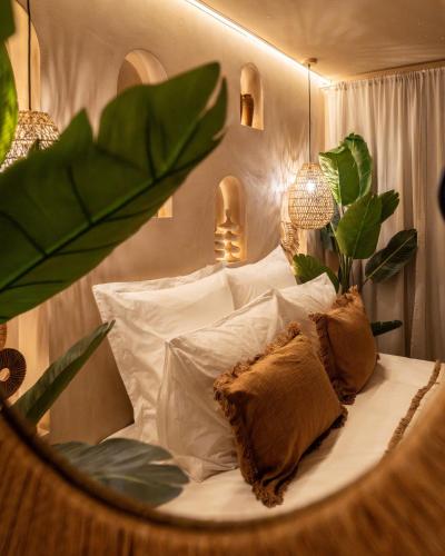 a bedroom with a bed with white pillows and plants at Cenote Suite - Expérience sensorielle in Le Havre