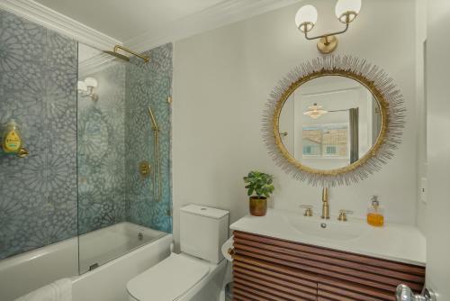 a bathroom with a tub and a toilet and a mirror at Modern European Townhouse in Vista