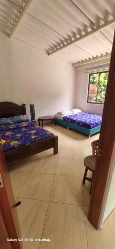 a room with two beds and a chair in it at Finca El Paraíso in Villeta
