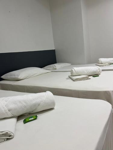 three beds in a room with a bottle on the table at Vila Mar Eco Hotel in Parnaíba