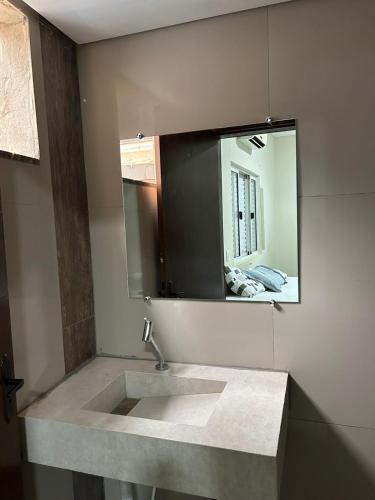 a bathroom with a sink and a mirror at Hotel Acácia in Tangara da Serra