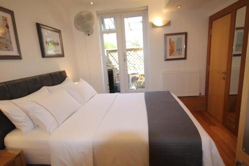 a bedroom with a bed with white sheets and a window at Cambridge city centre immaculate 2 bed apartment in Cambridge