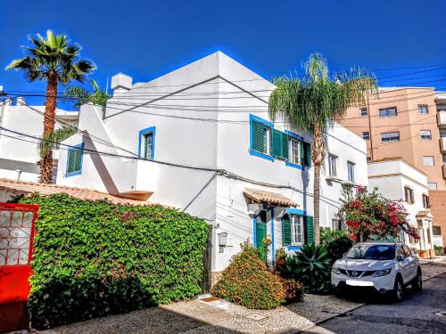 een wit huis met palmbomen en een auto bij Casa Rustica - Courtyard House in Olhão