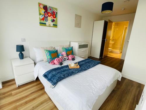 a bedroom with a white bed with stuffed animals on it at Modern & Cosy Apartment With Balcony, Near Media City Centre & Old Trafford Stadium in Manchester