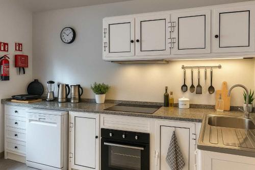 a kitchen with white cabinets and a sink at Casa Joao Batista em Machico in Machico