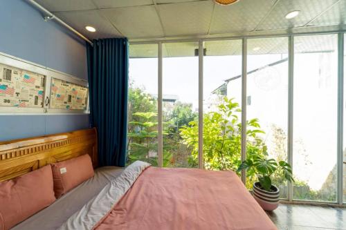 a bedroom with a bed and a large window at Dalat inn homestay hẻm 48 hà huy tập in Teurnoum