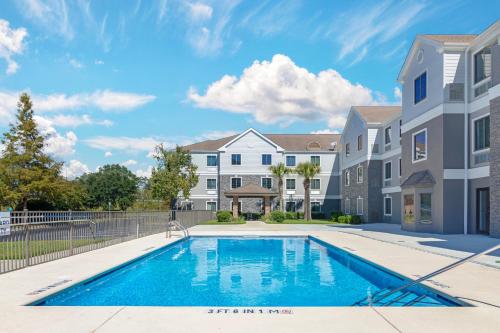 a swimming pool in front of a building with a house at Comfort Inn & Suites Savannah Airport in Savannah