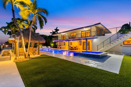 a house with a swimming pool and palm trees at Deep Blue Waterfront Gem Pool Kayaks Dock in Key Colony Beach