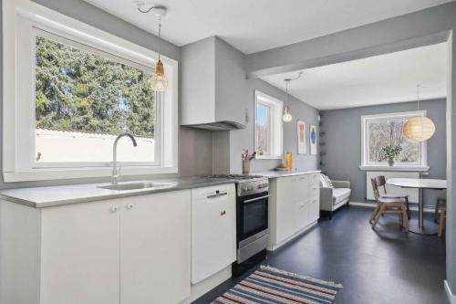 une cuisine avec des placards blancs et une grande fenêtre dans l'établissement Rummeligt Feriehus På Stor Naturgrund, à Langedeby