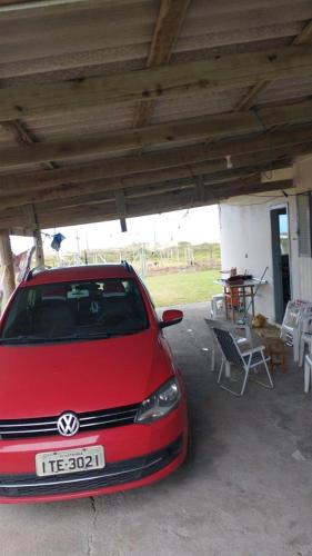 a red car parked under a building with a table at Casa de Veraneio in Passo De Torres