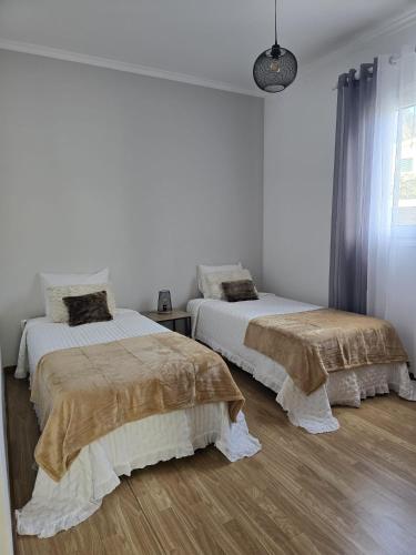 two beds in a room with white walls and wood floors at Casa da Cruz in Porto da Cruz
