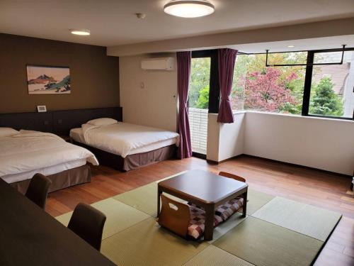 een slaapkamer met twee bedden, een tafel en een raam bij City Pension Zem in Tokyo