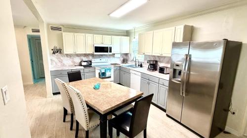 a kitchen with a table and a stainless steel refrigerator at Escape near to Siesta Key with Hot Tub, BBQ, and Fire pit in Sarasota