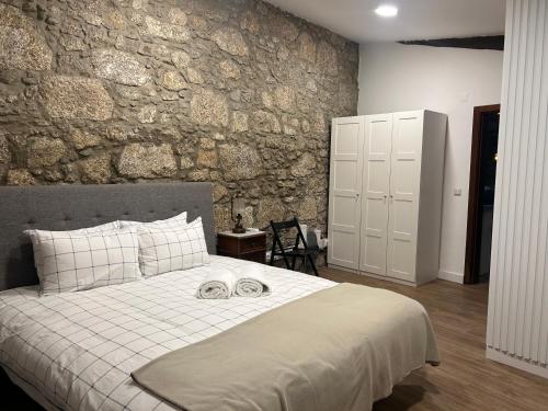 een slaapkamer met een groot bed en een stenen muur bij Casa Do Refugio Guest House in Covilhã