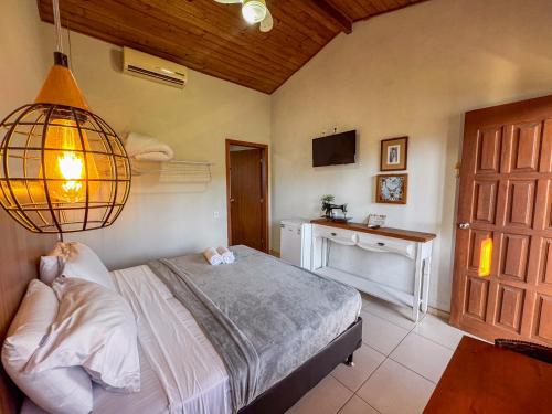 プライア・ド・ローザにあるPousada Lagoa do Rosaのベッドとシャンデリアのある寝室