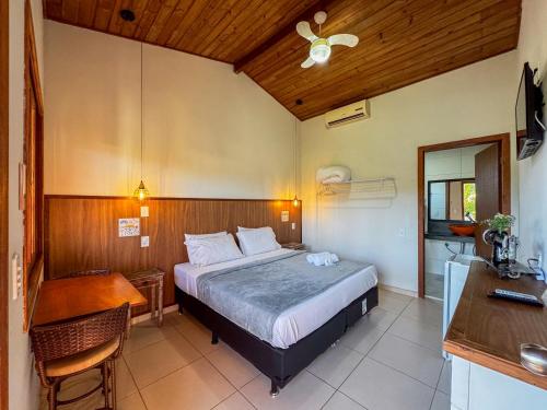 プライア・ド・ローザにあるPousada Lagoa do Rosaのベッドとテーブルと机のある寝室