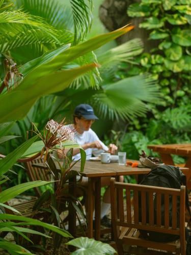 a man sitting at a table in a garden at Hostik Hostal in Mérida
