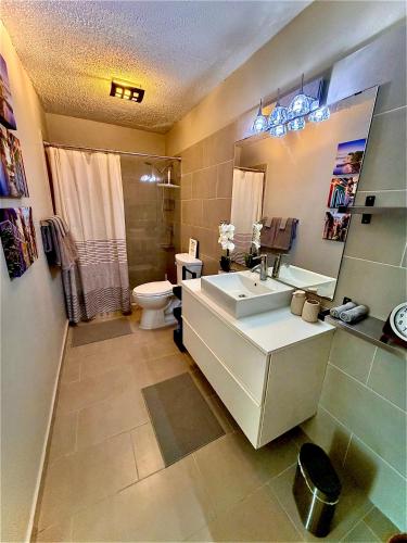 a bathroom with a sink and a toilet and a mirror at Stylish Designed 1BR Coral Beach by Stay Here PR in San Juan